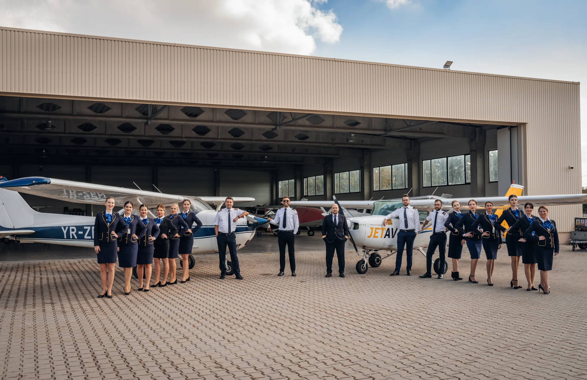 Grup de cursanți și piloți lângă avion, la hangar