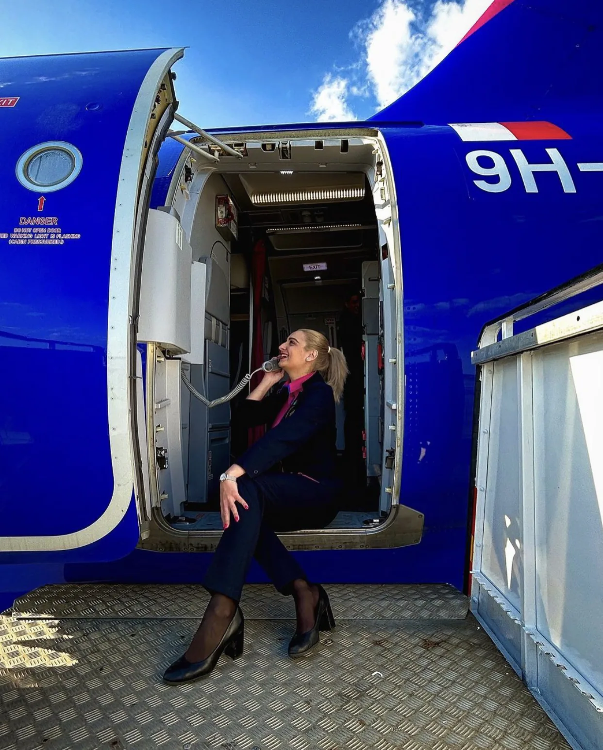 Însoțitoare de bord în ușa unui avion de pasageri