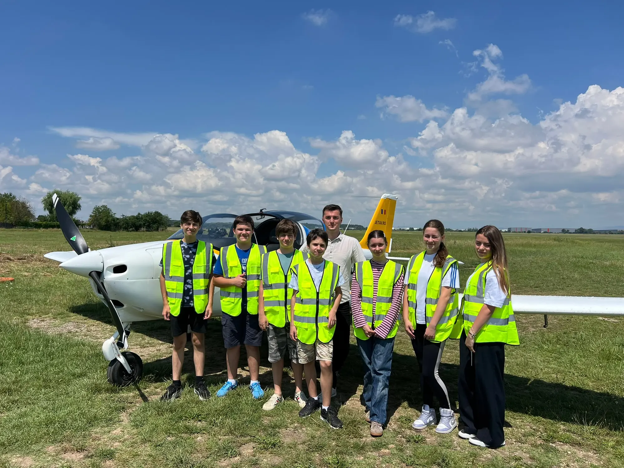 Elevi cu veste galbene lângă avion la aerodrom